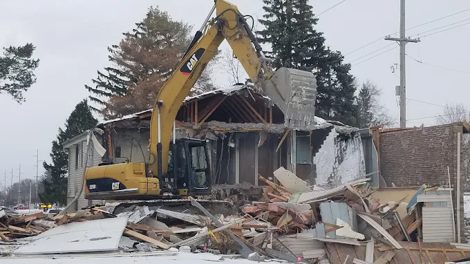 Cat 320D excavator demolishing a two-story house