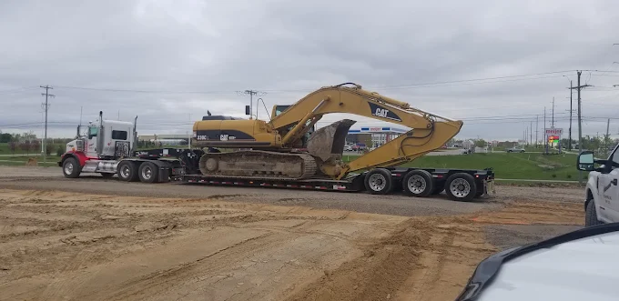 Lowboy hauling a Cat 330C excavator down the highway